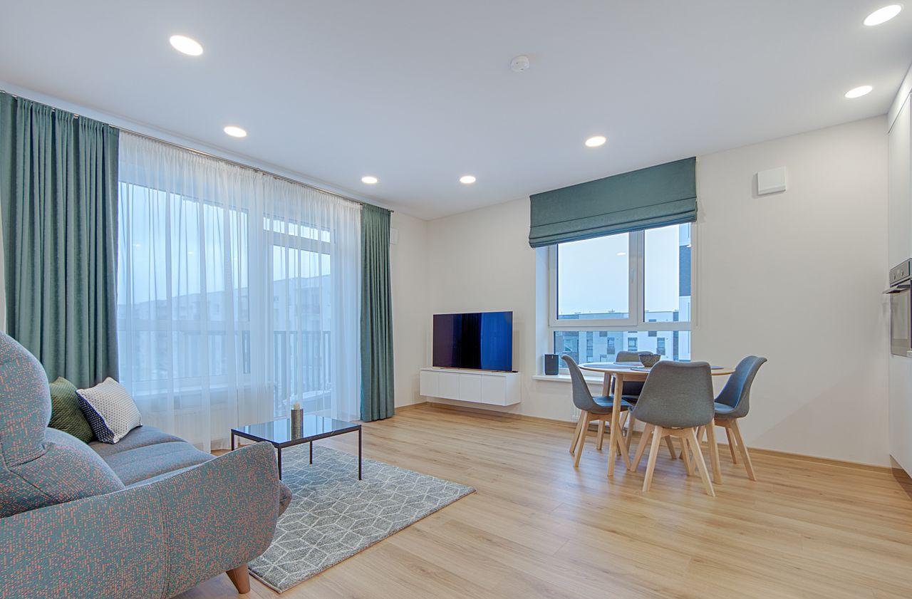 Spacious and stylish living room with dining area in a modern Lithuanian apartment.