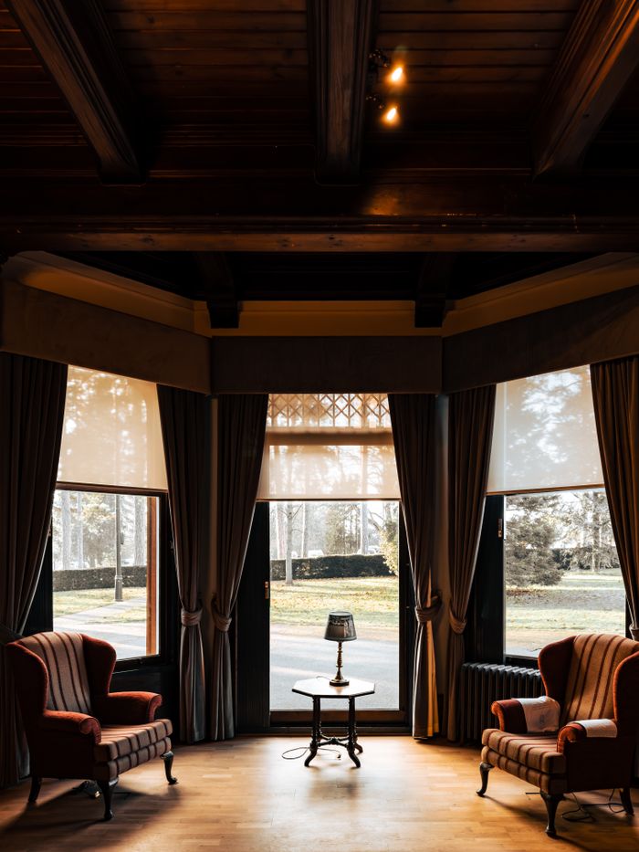 Cozy living room interior featuring elegant armchairs and large windows with curtains, perfect for a relaxing ambiance.